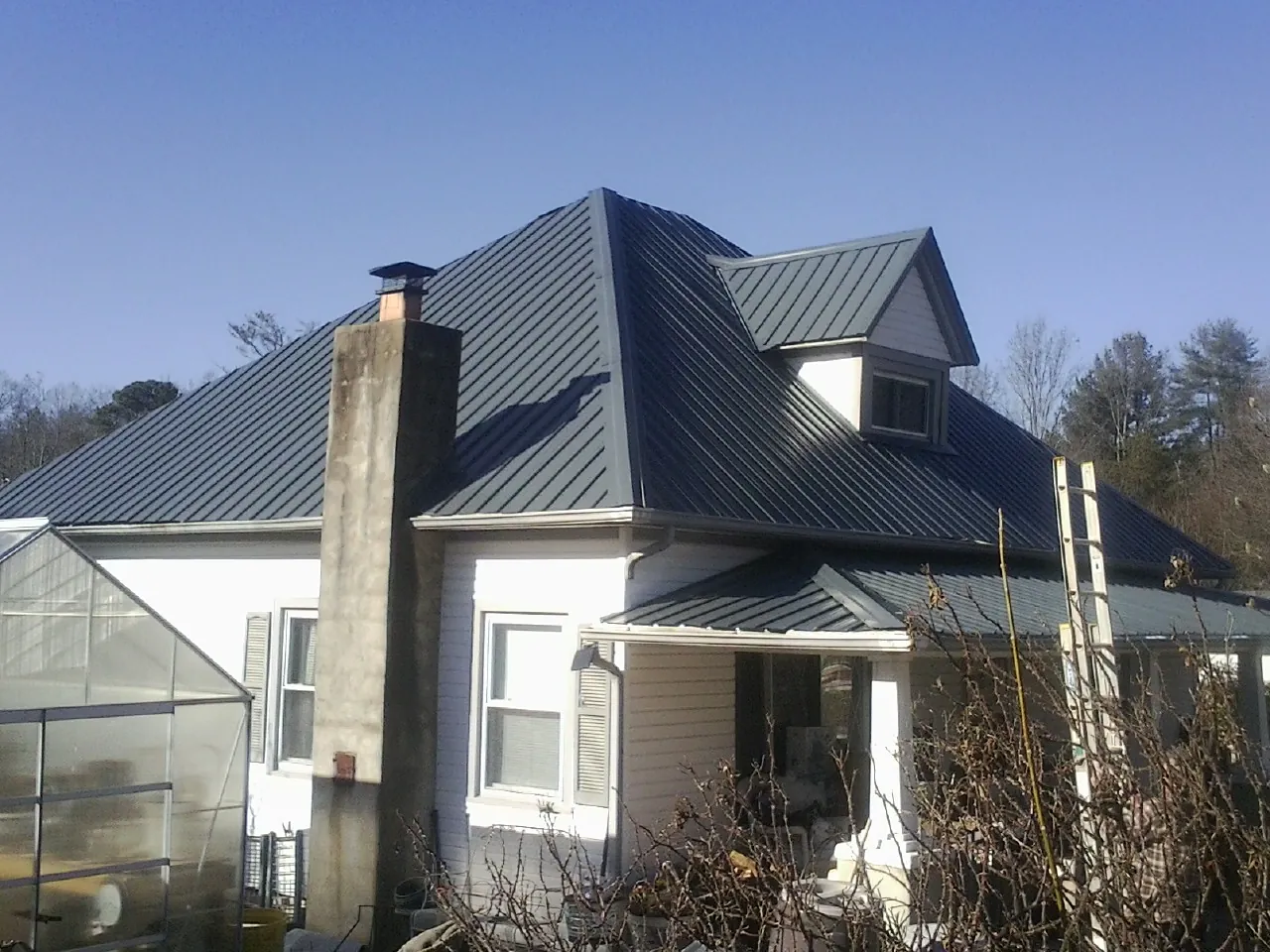 Dark blue standing seam metal roof on a white farmhouse with dormer — Slate & Tile Roof Repair by Roofing Brothers in Esopus