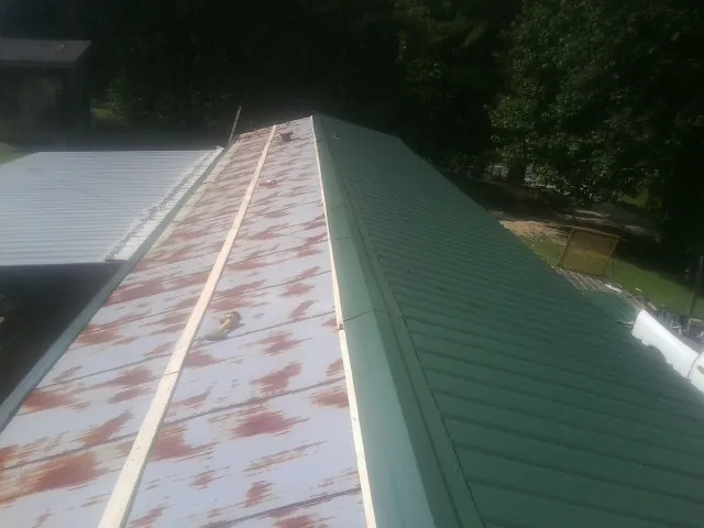Old rusted panels beside newly installed green metal roofing — Wind Damage Roof Repair by Roofing Brothers in Esopus