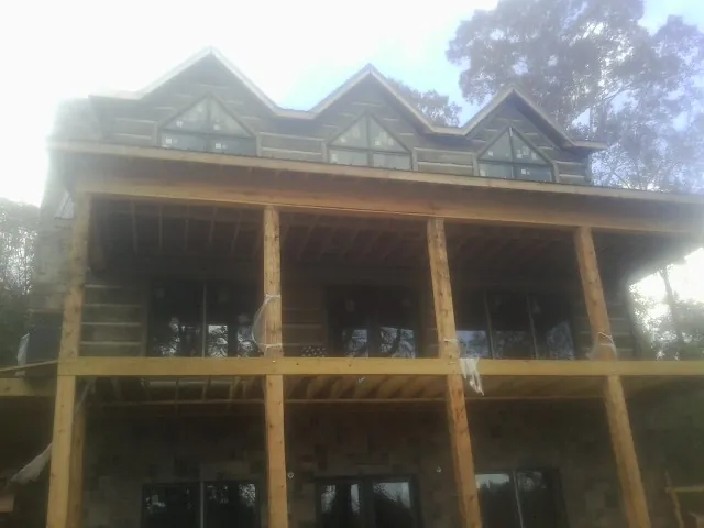 Dormers and porch framing on a large log home under construction — Roof Coating work by our crew in Esopus