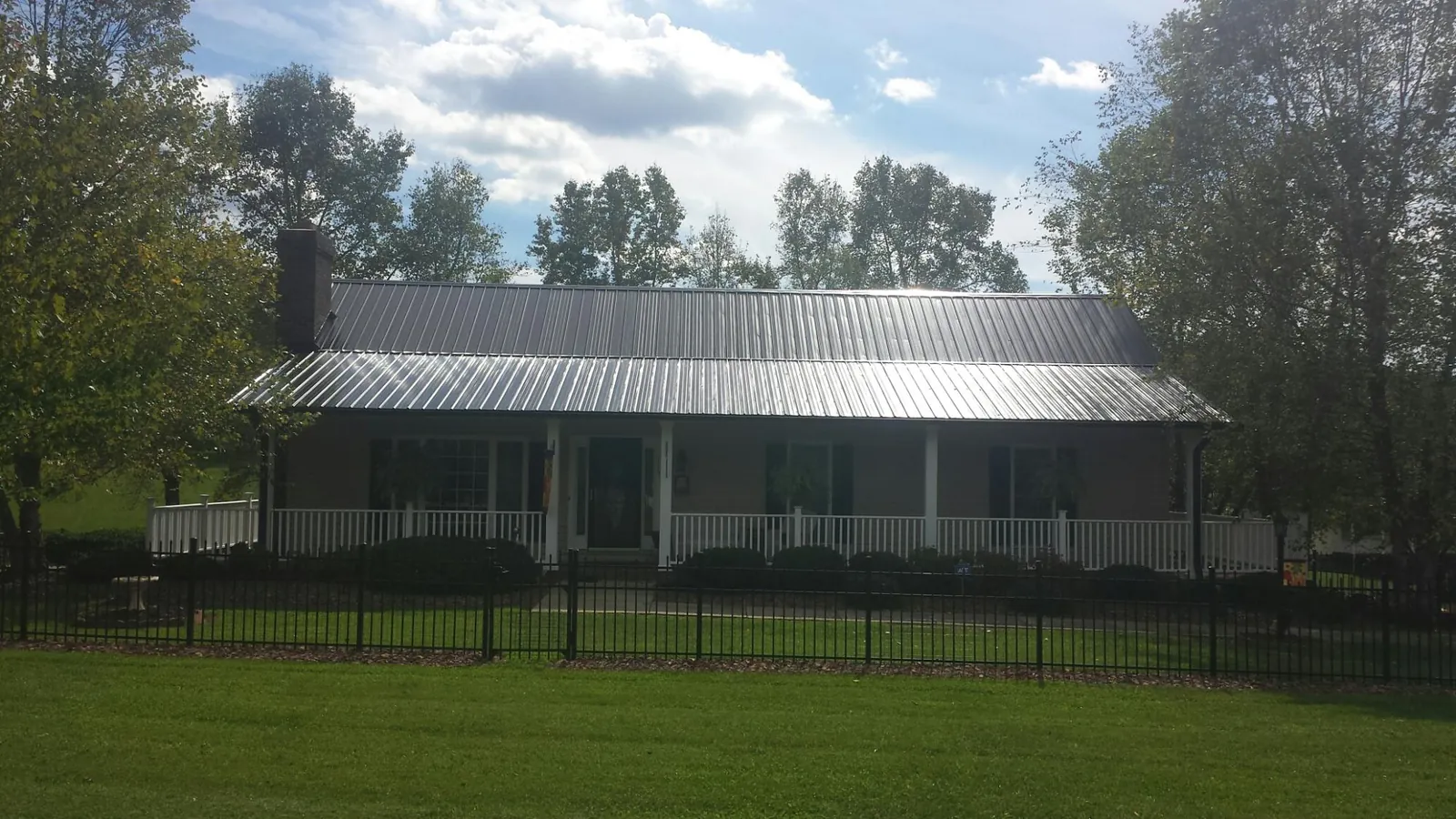 Gray metal roof on a brick ranch with a full width front porch — Gutter Guard Installation work by our crew in Esopus