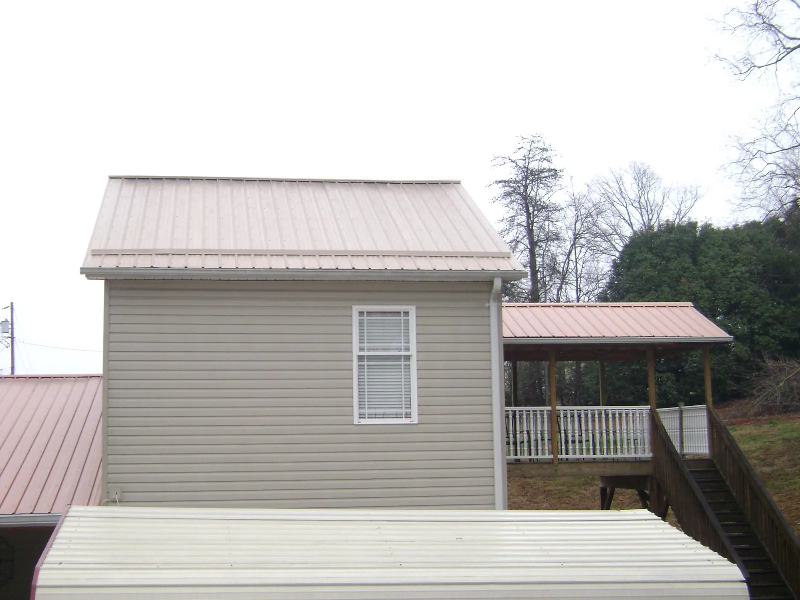 Tan metal roofs on a two story addition and attached porch, from a Roof Replacement job in Esopus